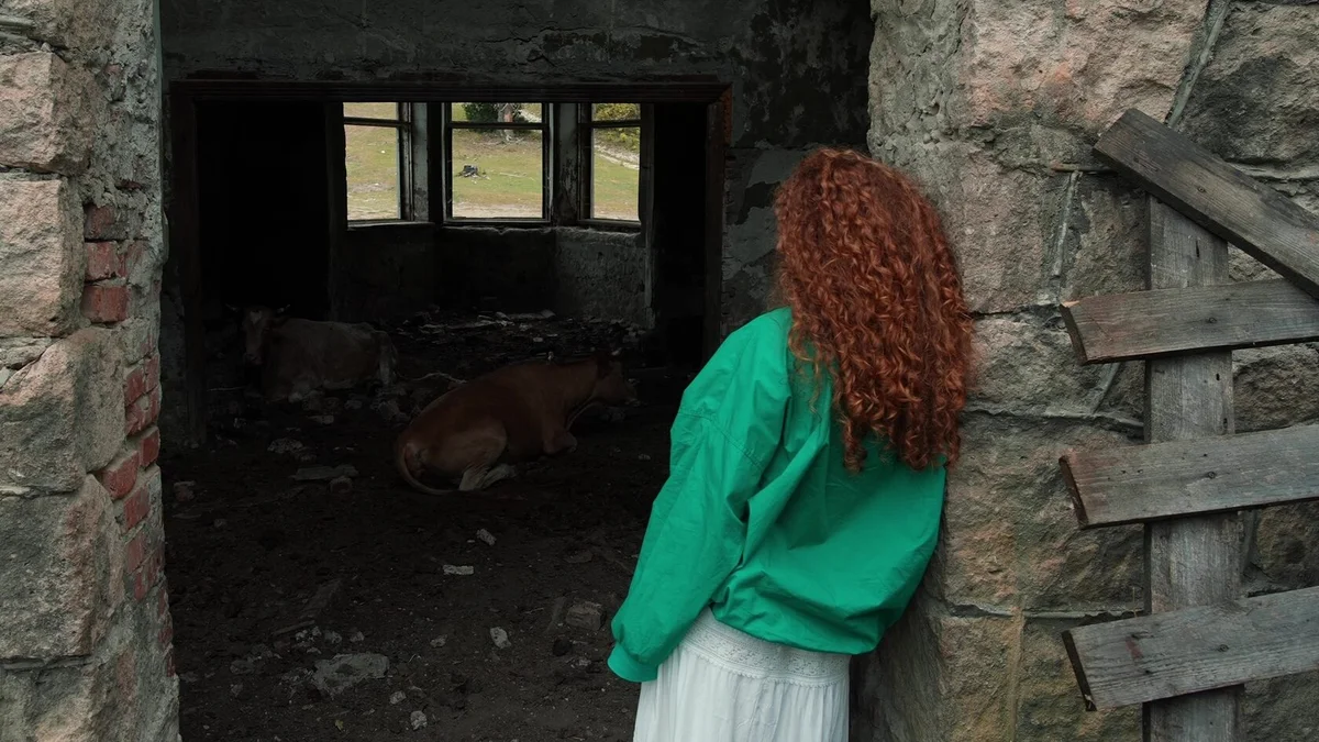 В горах. Она